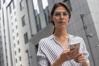 Yakın genç ofis kadın sakin ciddi yüz ifadesi ile mesafe içine bakarken cep telefonundan biriyle konuşurken. Büyük patron, yönetici, işçi, iş kadını takım lideri