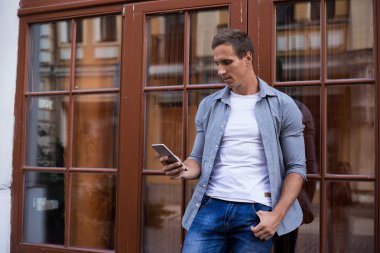 Ciddi yönetici new york'ta bina yakınında 4g internet ile cep telefonu kullanarak iş hakkında e-posta okuma akıllı telefon haberleri arıyor. Kendinden emin ciddi adam online iş olan