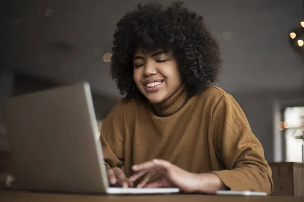 Genç bir işçi, bir stajyer, afro-Amerikalı bir kadın, bir dizüstü bilgisayar için çalışıyor, internet kaynakları, sosyal ağ kullanımı yoluyla bilgi arar. Ofisteki bilgisayarbaşında çalışmak