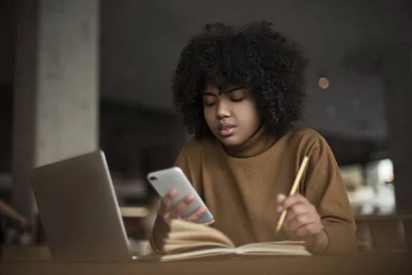 A young worker, an intern, an african-american woman, works for a laptop, searches for information through the use of Internet resources, social networking. Work at the computer in the office