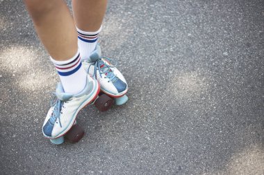Çekici genç kız yolda yeşil ağaçlar arasında bir parkta sokakta şık dörtlü paten sürmek. O paten üzerinde disko dans yapar, müzik dinler, eğlenir ve zevk