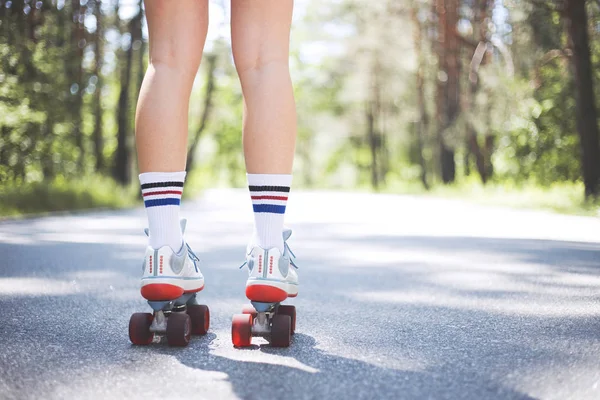 魅力的な若い女の子は 道路上の緑の木々の間の公園で通りでスタイリッシュなクワッドスケートに乗ります 彼女はローラースケートでディスコダンスを行い 音楽を聴き 楽しみ 楽しんでいます — ストック写真