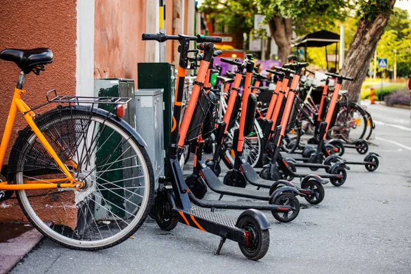 Many scooters and bicycles in the parking lot. Electric vehicle rental to move around the city. Technological gadgets and modern technology in transport. ECO concept, ecology care. Trendy transport.