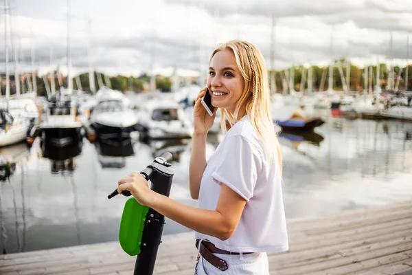 Kiralık E-scooter, modern mobil teknolojiler tarafından self servis. Çevre dostu, elektrikli ulaşım. Kadın hipster kiralık scooter, elektro hareketlilik. Eko kavramı. Telefon arama ve bağlantı noktası yakınında sürüş.