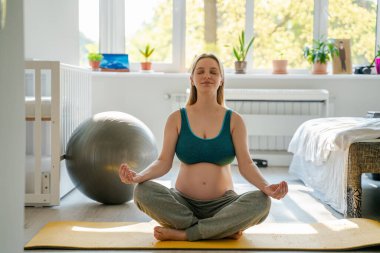 Hamile bir kadın sabahları yoga ve rahatlama egzersizleri yapar. Anneliğe ve çocuğun doğumuna hazırlanır. Doğuma hazırlanır.