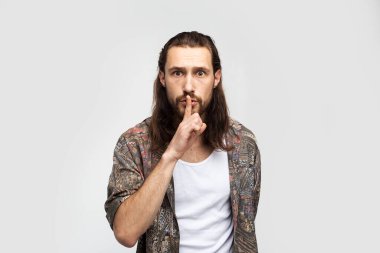 Request for silence. Dumb man, demands silence gesture and be quieter. Hipster traveler stylish carefree man on a white studio background, people lifestyle