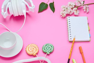 bir genç çocuğun masanın üst görünümü, pembe arka plan üzerinde içecek kulaklık Lolipop ile dizüstü silgi çiçek cam için kalem kompozisyon