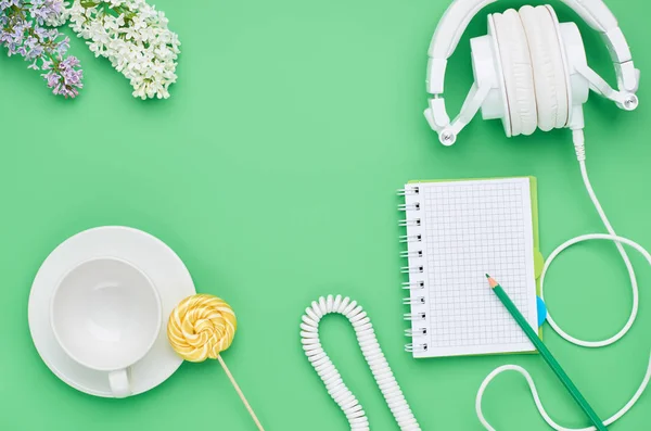 Vista superior de la mesa de un niño adolescente, composición auriculares portátil flor lápiz vidrio vacío piruleta sobre fondo verde claro — Foto de Stock