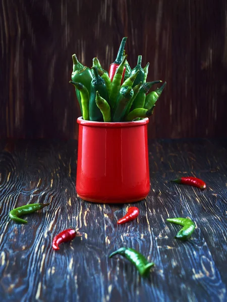 Pimientos verdes en una taza roja sobre una mesa de madera —  Fotos de Stock