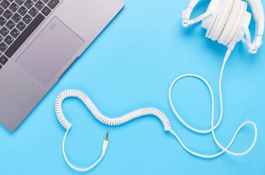 mavi arka plan üzerinde gadget'lar üzerine üst görünüm, bir kalp şeklinde bir tel ile bir dizüstü bilgisayar ve beyaz kulaklık kompozisyon