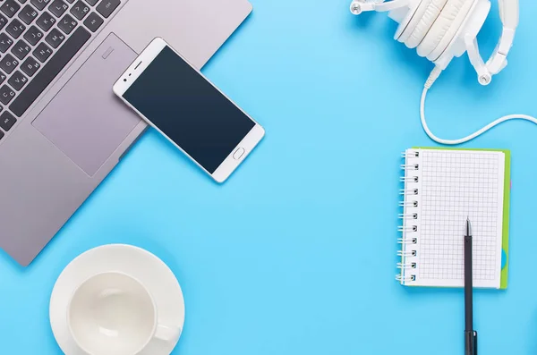 Vista superior sobre gadgets sobre fondo azul, la composición de un ordenador portátil, auriculares blancos, teléfono, vidrio con una bebida y llaves del coche — Foto de Stock