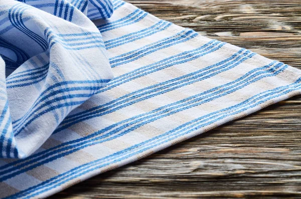 Old dark wooden background. Wooden table with blue and white kitchen towel