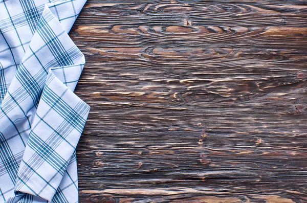 Old dark wooden background. Wooden table with green tea towel