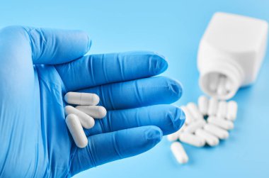 Genç insan eli hapları avuç içinde tutar. Sağlık sigortası, tıbbi ve ilaç konsepti. Mavi arkaplanda izole.