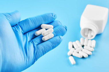 Genç insan eli hapları avuç içinde tutar. Sağlık sigortası, tıbbi ve ilaç konsepti. Mavi arkaplanda izole.