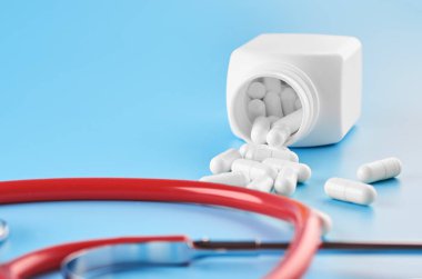 Pills tablet kapsülleri yakın çekim. Mavi bir arka plan, bir kavanoz ilaç. Mavi bir arka plan, bir kavanoz ilaç ve bir stetoskop..