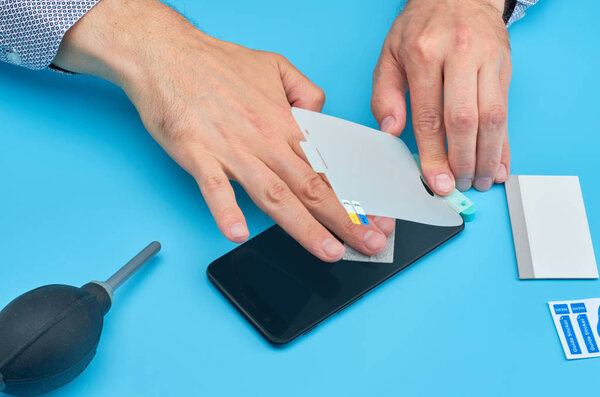 The man replacing the broken tempered glass screen protector for smartphone.