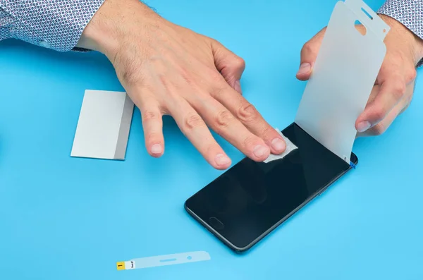 The man replacing the broken tempered glass screen protector for smartphone.