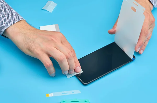 The man replacing the broken tempered glass screen protector for smartphone.