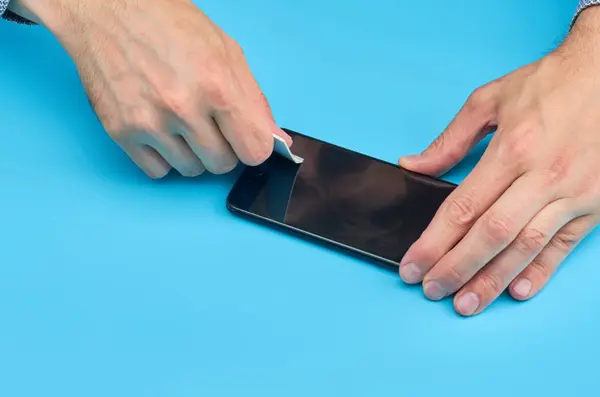 El hombre que reemplaza el protector de pantalla de vidrio templado roto para teléfono inteligente . — Foto de Stock