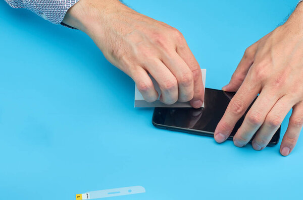 The man replacing the broken tempered glass screen protector for smartphone.