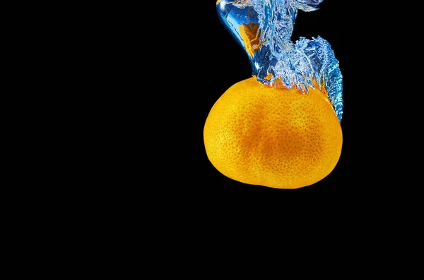 Frische Mandarine fällt ins Wasser mit Spritzer auf schwarzem Hintergrund — Stockfoto