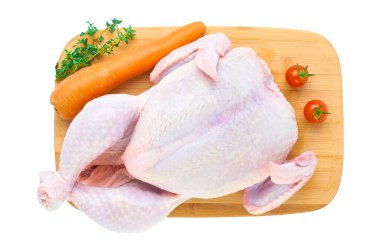 Tahta kesme tahtasındaki taze çiğ tavuk leşi, beyaz arka planda izole edilmiş sebzelerle. Yukarıdan görünüşü.