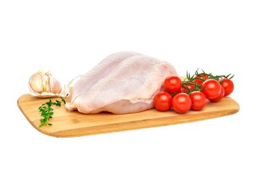Tahta kesim tahtasında taze çiğ tavuk göğsü, beyaz arka planda sebzeler ve otlarla. Kapat..