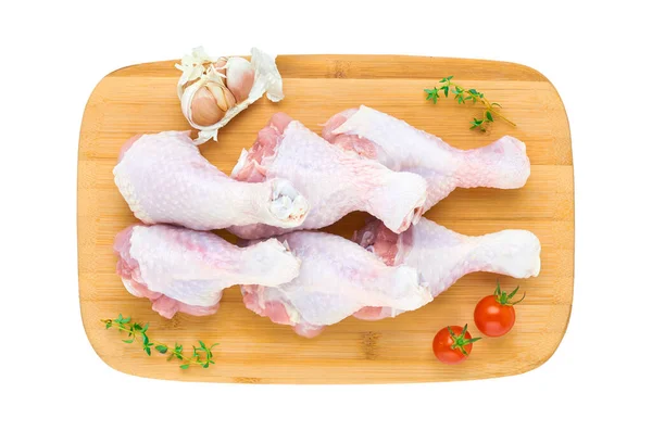 白い背景に野菜やハーブが隔離された木製のまな板の上に6つの新鮮な鶏のドラムスティックのセット 上からの眺め — ストック写真