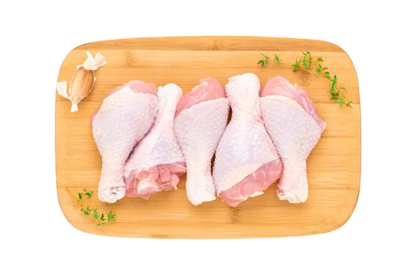 白い背景に野菜やハーブが隔離された木製のまな板の上に5つの新鮮な鶏のドラムスティックのセット 上からの眺め — ストック写真