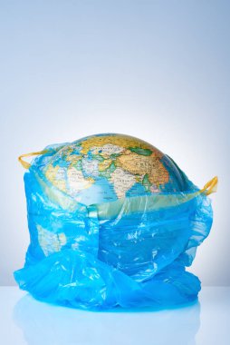 Dünyayı plastik atıklardan koruma kavramı, çevre kirliliğiyle mücadele, çevre için mücadele, hafif arka planda mavi bir çöp torbasında bir dünya. Poşet yok.