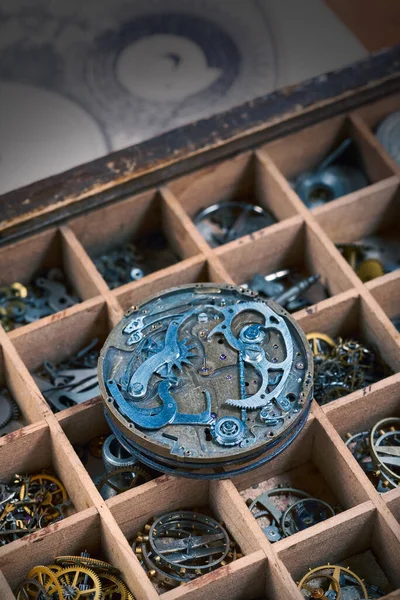 An old watch movement is lying on a box with various watch details, close-up.