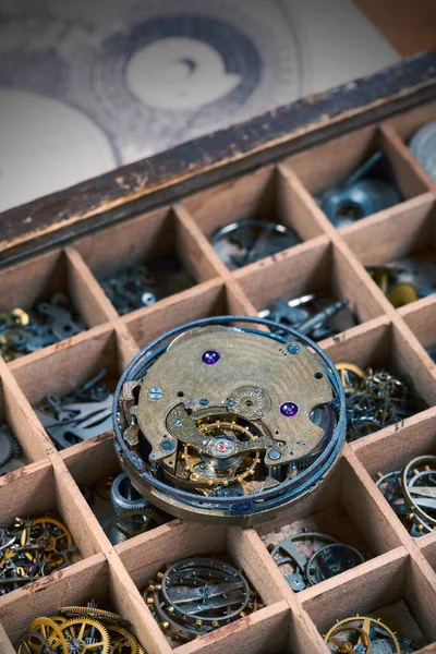 An old watch movement is lying on a box with various watch details, close-up.