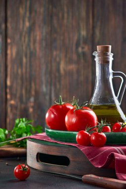 Bir şişe zeytinyağıyla tepside taze kırmızı domatesler. Sebzelerin güz hasadıyla hayat.