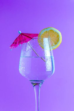 Kokteyl limon dilimi ve şemsiye ile mor arka planda izole