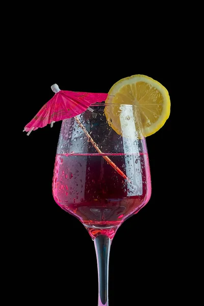 Koktejl izolovaný v černém pozadí s citronovou výsečí a deštníkem — Stock fotografie