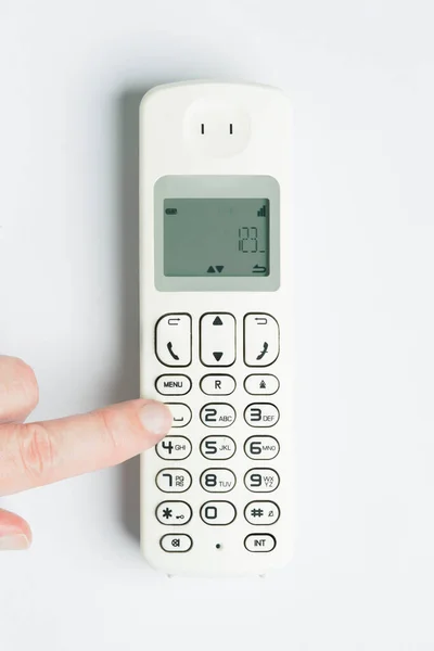 hand dialing on a wireless landline phone on white background