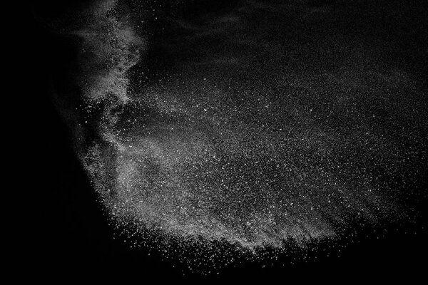 Замораживание движения белых частиц на черном фоне. Взрыв порошка. Абстрактная пылевая текстура.