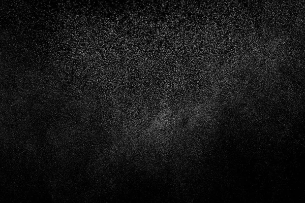 Siyah arka planda soyut su sıçramaları. Beyaz parçacıkların hareketlerini dondur. Yağmur, kar örtüsü dokusu.