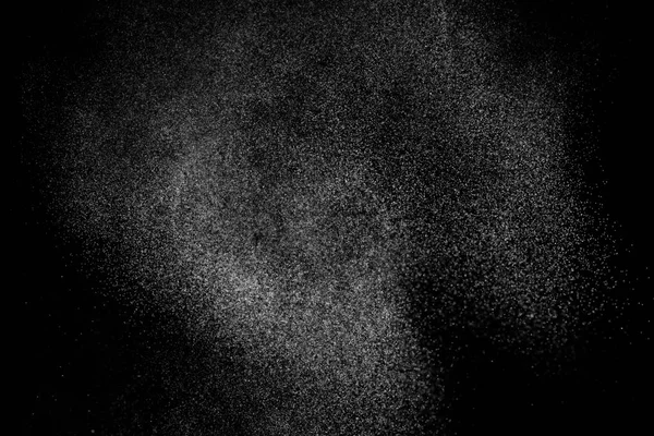 Siyah arka planda soyut su sıçramaları. Beyaz parçacıkların hareketlerini dondur. Yağmur, kar örtüsü dokusu.