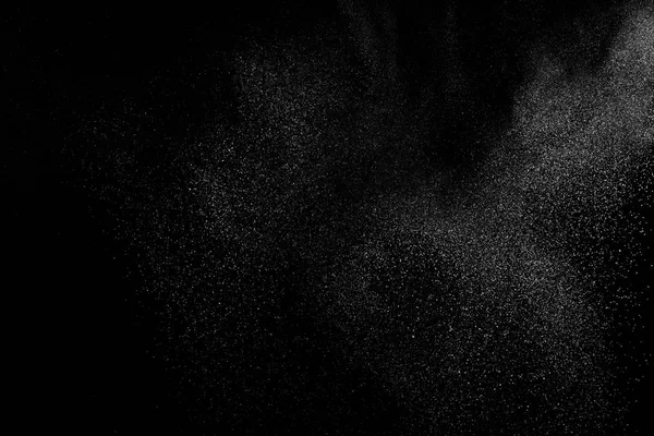 Siyah zemin üzerindeki beyaz parçacıkların hareketlerini dondur. Barut patlaması. Soyut toz tabakası dokusu.