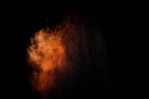 Orange powder explosion on black background. Colored powder cloud. Colorful dust explode. Paint Holi.