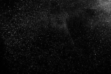 Siyah zemin üzerindeki beyaz parçacıkların hareketlerini dondur. Barut patlaması. Soyut toz tabakası dokusu.