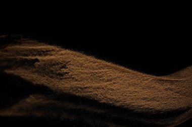 Kum dalgası siyah arkaplanda izole edildi. Soyut kum tepeciği.