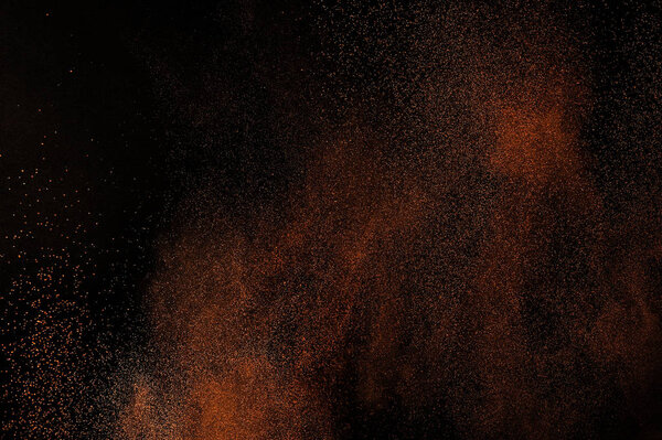 Orange powder explosion on black background. Flame cloud. Yellow dust explode. Freeze motion paint Holi.