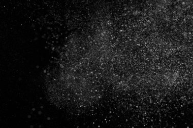 Siyah zemin üzerindeki beyaz parçacıkların hareketlerini dondur. Barut patlaması. Soyut toz tabakası dokusu.