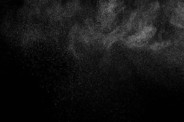 Замораживание движения белых частиц на черном фоне. Взрыв порошка. Абстрактная пылевая текстура.