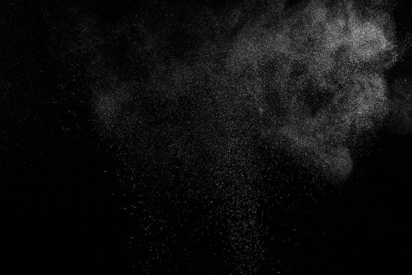 Замораживание движения белых частиц на черном фоне. Взрыв порошка. Абстрактная пылевая текстура.