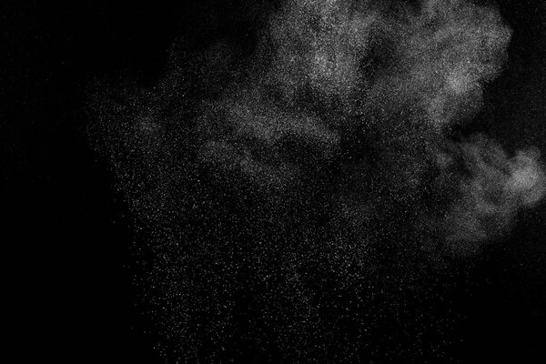 Замораживание движения белых частиц на черном фоне. Взрыв порошка. Абстрактная пылевая текстура.