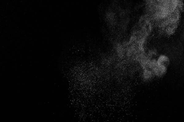 Замораживание движения белых частиц на черном фоне. Взрыв порошка. Абстрактная пылевая текстура.